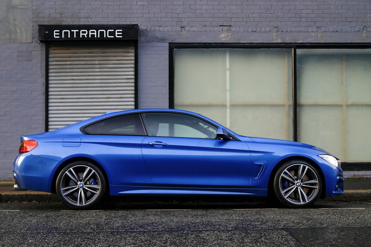 Blue coupe parked on a city street