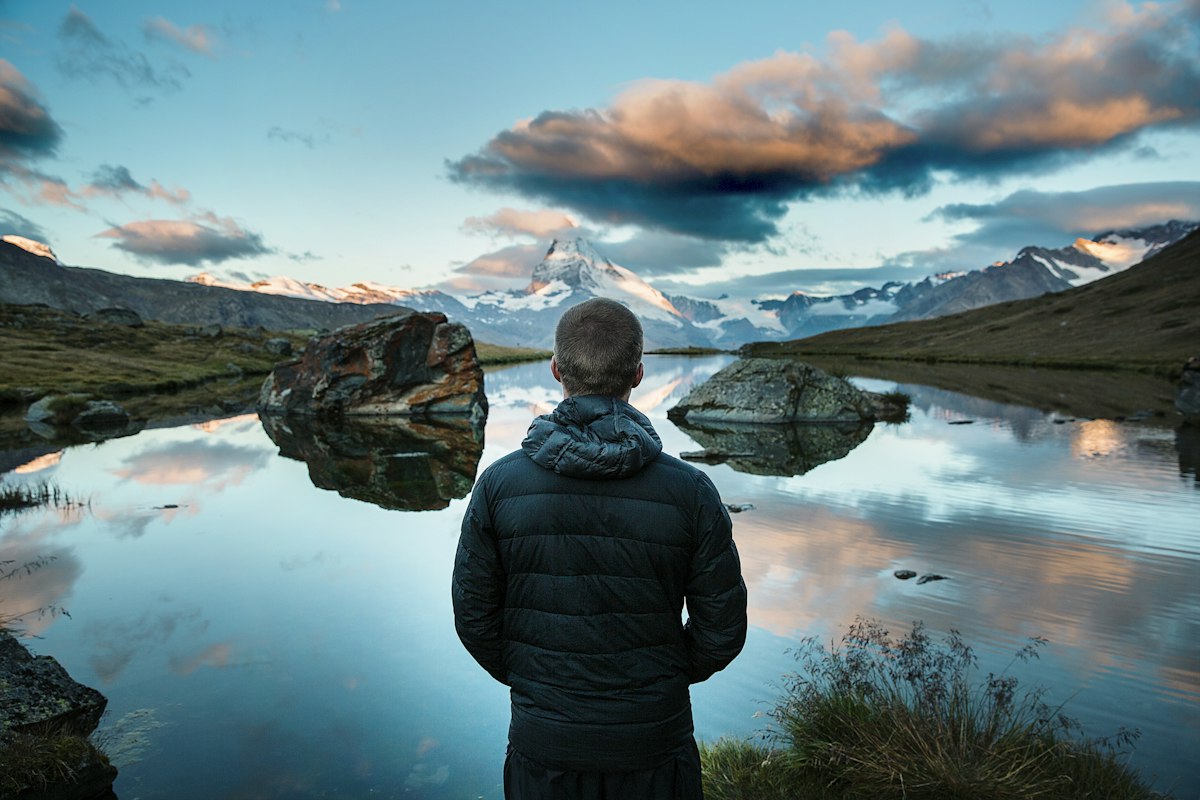 Person looking out over a mountain lake at dusk, reflecting on the future