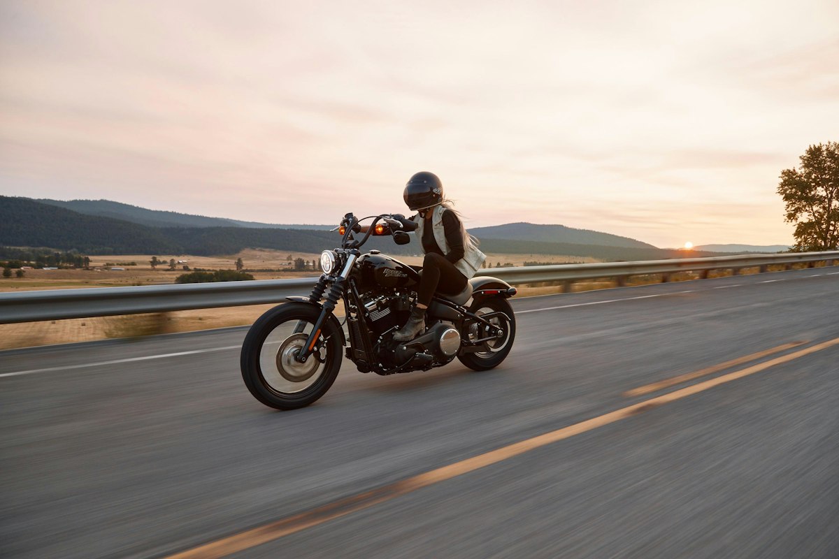 Motorcyclist riding a cruiser motorcycle on an open highway at sunset