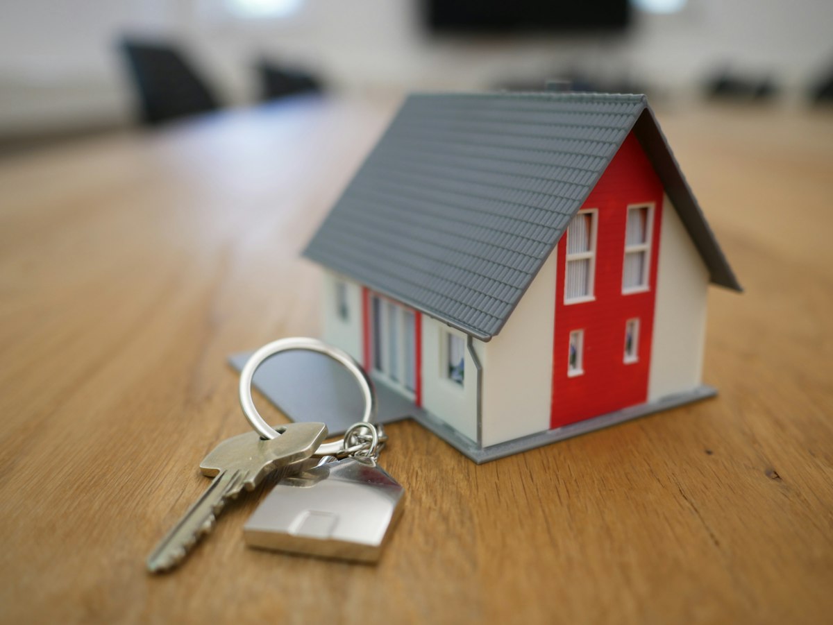 Small model house next to a set of house keys on a table